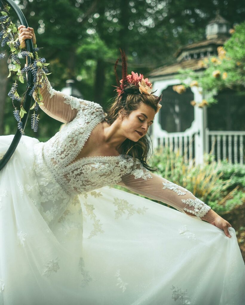 Stunning Mirror Mirror Bride posing in her wedding dress while performing on her cyr wheel.