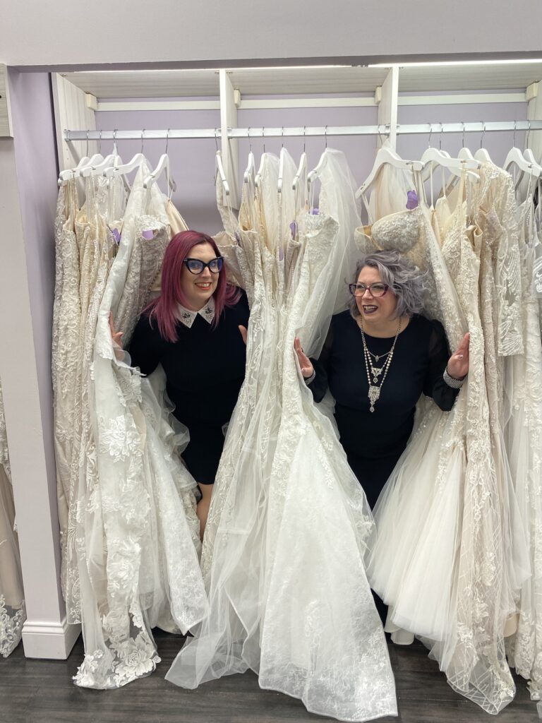 Mirror Mirror Owner and Manager hiding together in a rack of wedding dresses.