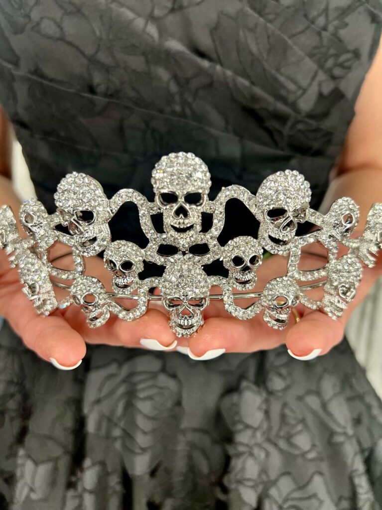 Mirror Mirror Bride to be posing in her black wedding dress with roses and holding a rhinestone skull tiara.