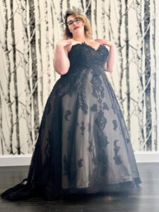 Stunning plus size bride wearing black wedding dress from Mirror Mirror Inc and posing in front of the wooded wallpaper.