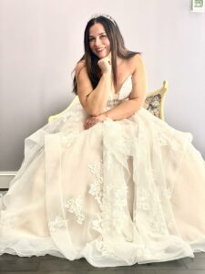 Happy Bride to Be sitting on a settee wearing a white princess wedding dress and matching tiara.