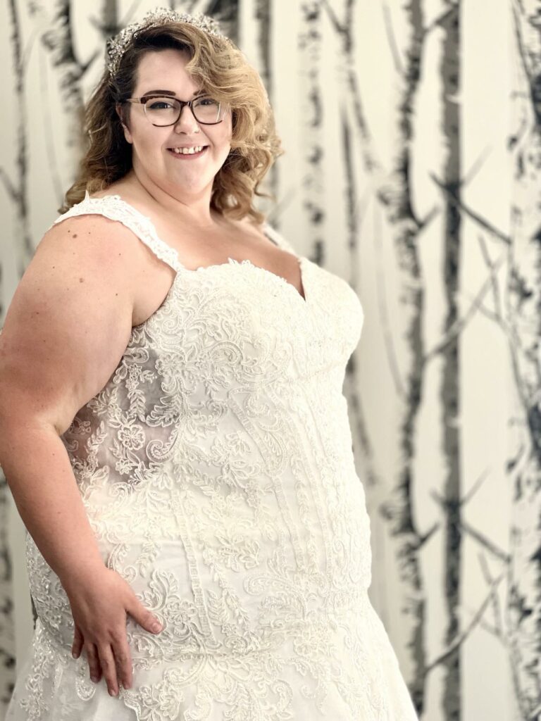 Confident plus size bride posing in her sleeveless bridal dress and peek-a-boo- sides.