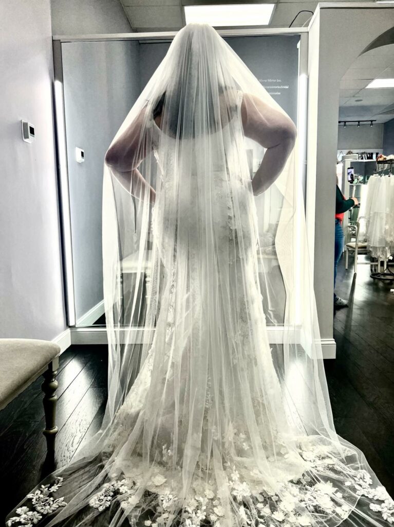 Curvy Plus Size bride posing in her lace mermaid wedding dress and embroidered wedding veil.