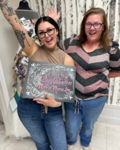 Two Mirror Mirror Inc. Brides to be posing with their "I met my Fairy Godmother at Mirror Mirror, Inc." sign after they chose their wedding dresses.