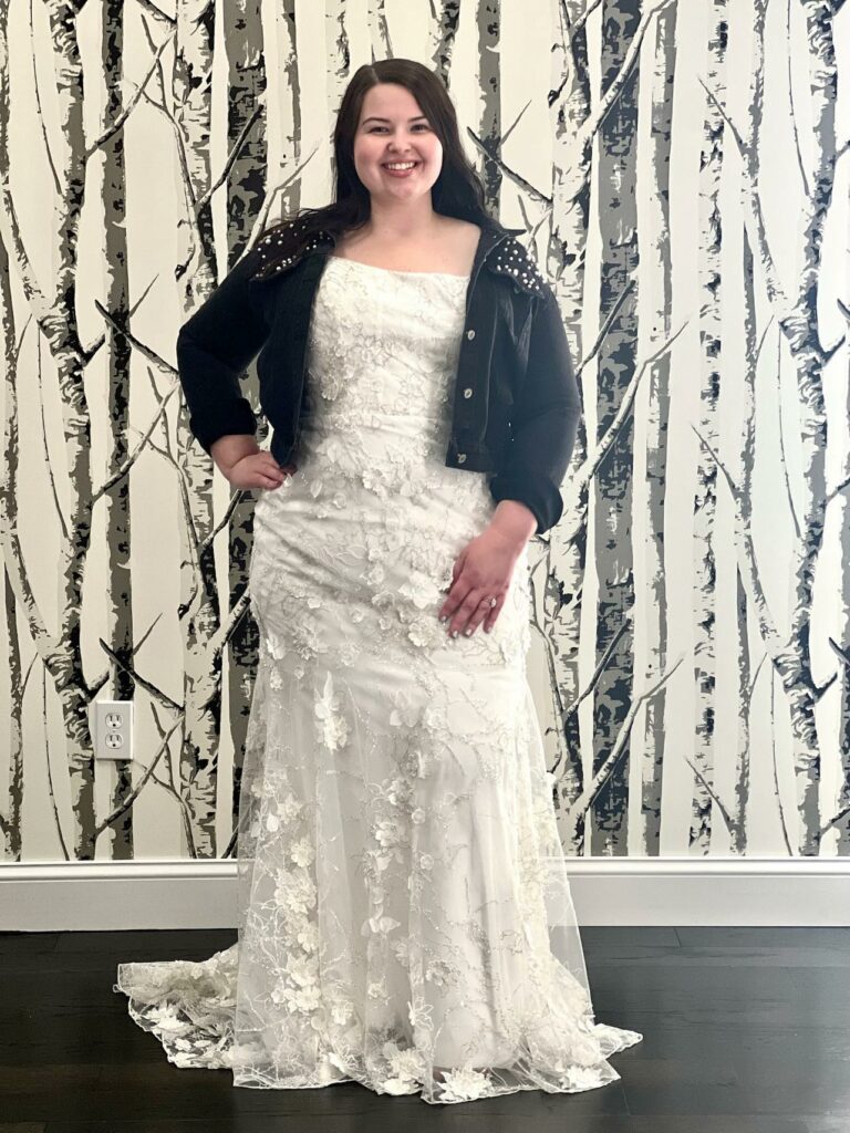 Lovely Mirror Mirror bride wearing a dark jean jacket and posing in her modest lace wedding dresses.