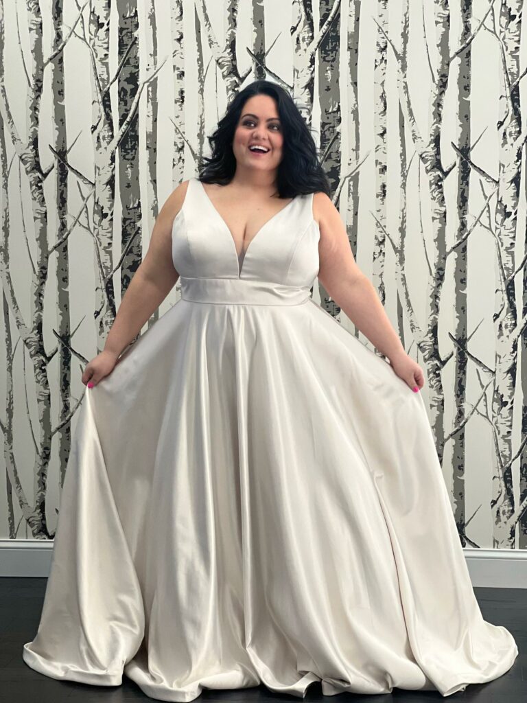 Happy Mirror Mirror bride posing in her plunging neckline, silk wedding dress.