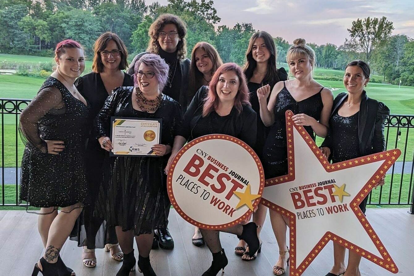 Mirror Mirror Bridal Boutique team holding their "Best Places to Work 2023" signs and smiling.